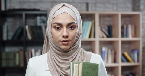 Female student wearing hijab confidently looking at camera. spending time in campus library studying - modern muslim concept close up 4k