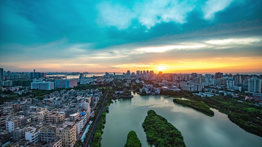 Haikou Cityscape Timelapse at Evening Blue Hour with Beautiful Twilight in the Sky, Cross-sea Bridge as Background and Hainan University Campus Lake in front. Capital City in Hainan Province of China.