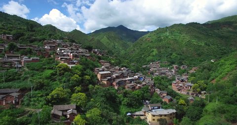 Aerial view of traditional asian village on green mountain. Flying over asian village in green forest mountain landscape.