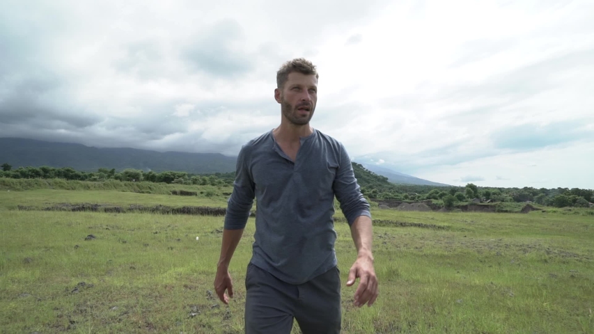 Very tired gloomy young man alone walking on the field. Slow motion.