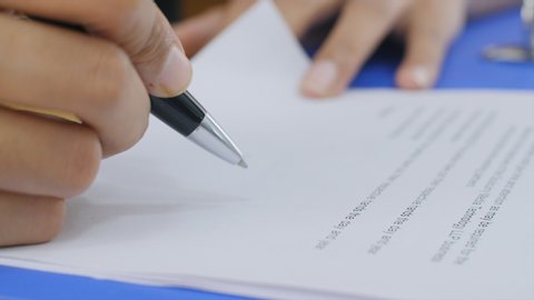 Closeup shot of a business woman / man signing a contract / legal agreement / paper. A businesswoman signing a contract with a partner