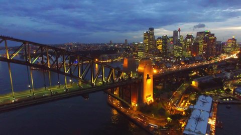 Slow motion of drone approaching Sydney at night from Sydney Harbor, Bridge and city skyline view