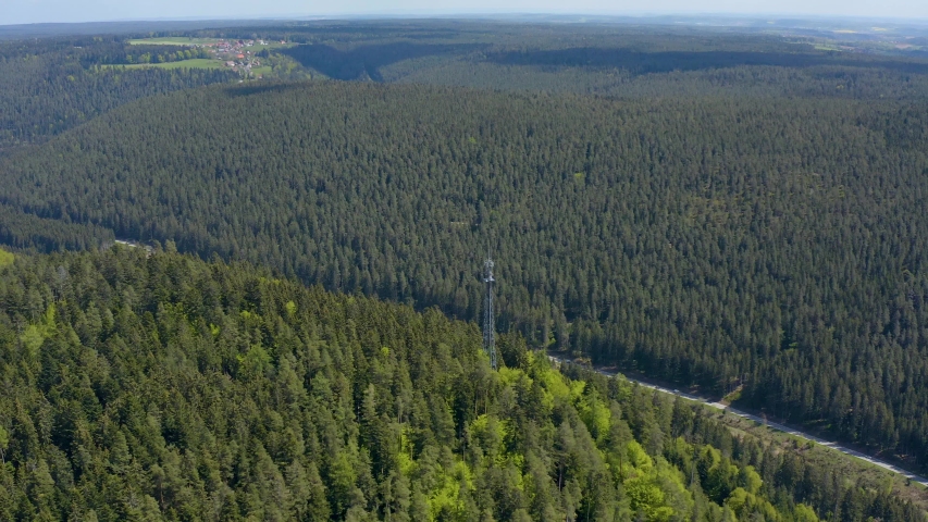 Pan to the left across the Black forest with a village far back.