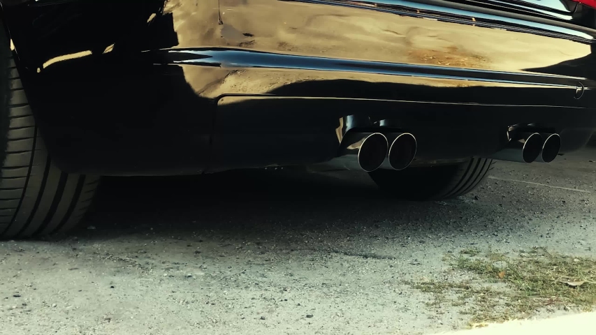 Black car. Smoke comes from the exhaust pipe