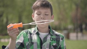 Portrait of cute small boy in checkered shirt blowing the soup bubbles close up. The child is having fun outdoors. Connection with nature. Summertime leisure - Powered by Shutterstock - Get 15% off with code: PIKWIZARD15