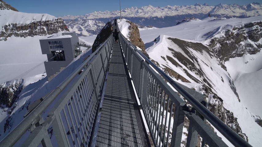 Tourists walking on Titlis Cliff Walk, suspension bridge at Mount Titlis in Engelberg, Switzerland 
