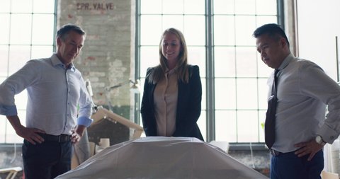 In modern, industrial office, architect reveals her scale model to her coworkers and they collaborate on urban planning project. Business and design thinking and collaboration. Shot on 4k RED camera.