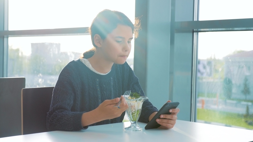 airport waiting for a flight by plane. Teen girl eats salad and looks smartphone. Internet in a cafe. terminal airport cafe. communicates lifestyle in the messenger