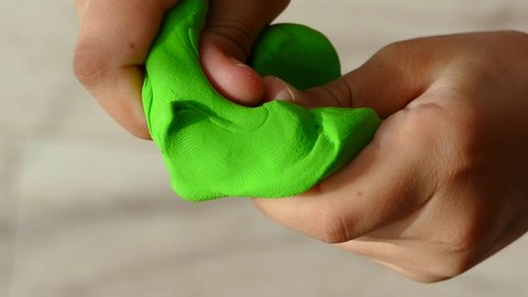 The child crumples in the hands of green clay. Children's games.