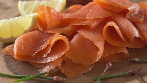 Close-up of sliced smoked salmon with lemon and chives.