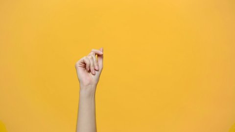 Woman hand snaps her fingers to music rhythm gesture isolated over yellow background in studio. Copy space for advertisement. With place for text or image. Advertising area, mock up.