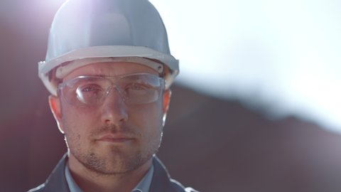 Close-up portrait of male industrial worker wearing glasses and helmet looking at camera