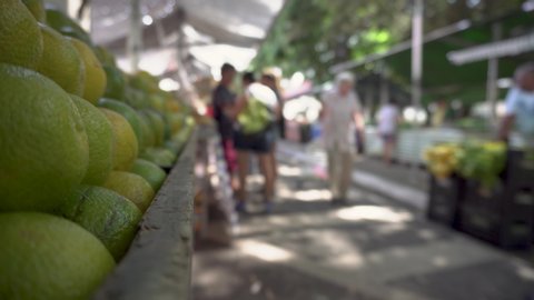 Selective focus on oranges and blurred image of people, shoppers at brazilian open-air marketplace, a free fair farmer Market on the street.
