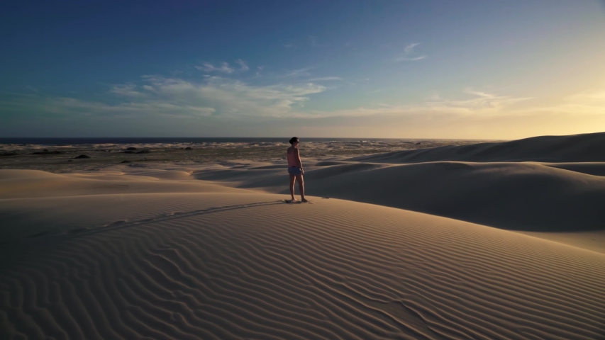 Cinematic Footage of Young Female Standing on Top of Dune And Watching Desert Hills With Footsteps in Sand and Beautitiful Skyline in Stockton Worimi National Park Australia 4k