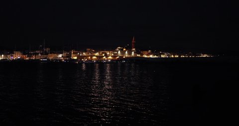 tilt up motion panoramic view of city centre of Alghero port at night