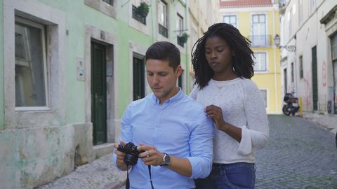 Smiling multiracial couple taking selfie with photo camera. Beautiful African American woman with dreadlocks hugging her Caucasian boyfriend during photographing. Photography concept