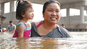 Little Asian baby girl, 25 months old, enjoys playing water in a river with her auntie - playing outdoor and engaging with nature provides positive impact on baby's health and development 