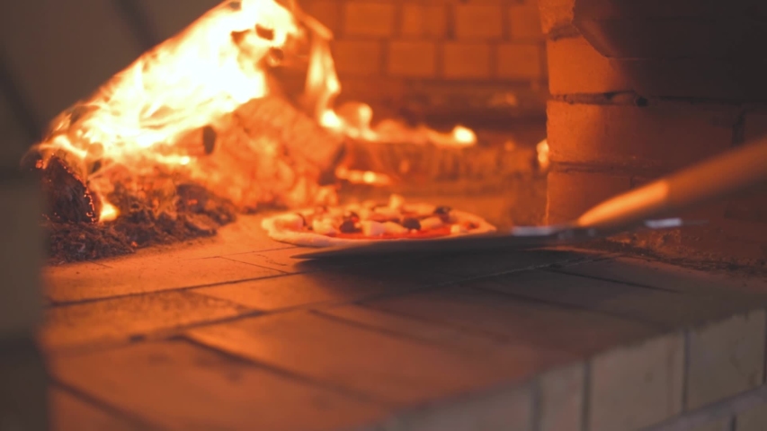 Placing Pizza in Wood fired Pizza Oven using a pizza peel Slow motion shot