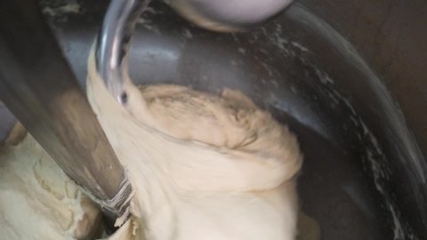 Close up for bread making process by using flour mixing machine in the factory. Stock footage. Preparation of dough with professional kneader machine at the manufacturing.