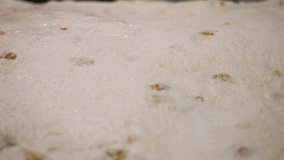 Close up for raw dough with small raisins ready for baking, delicious food concept. Stock footage. Raw pastry lying on the table at the bakery.