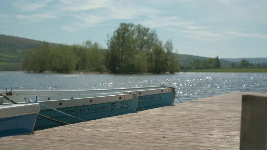 Row Boats lay moored side by side in a tranquil bay at Llangorse Lake