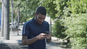 Medium shot of anxious young Caucasian man in dark blue T-shirt texting on phone outside, receiving good news, not believing his eyes, being touched. Lifestyle, communication concept