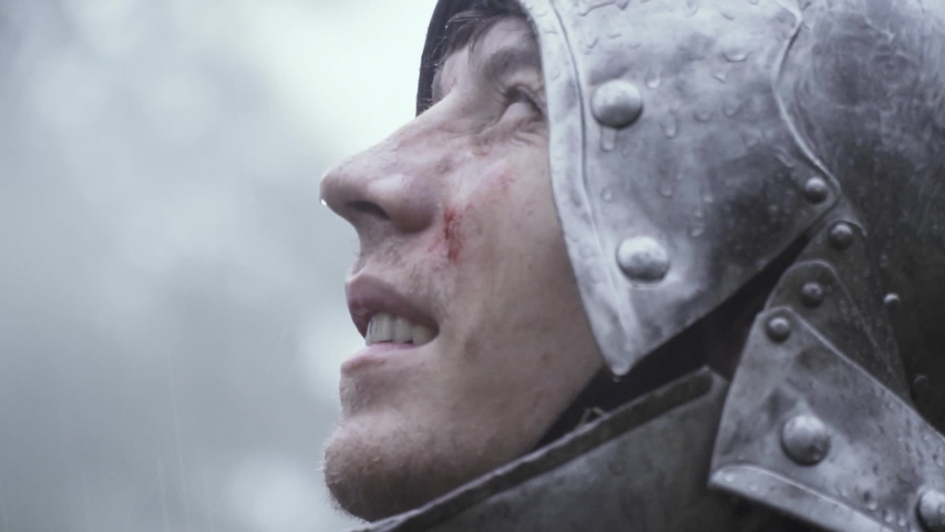 Close up of a medieval soldier with helmet on his head looking up