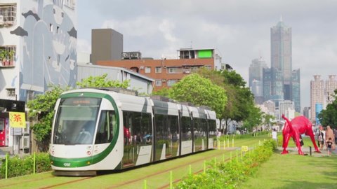 Kaohsiung, Taiwan - May 1, 2019: Tram of the Circular light rail KLRT passing between Penglai Pier-2 and Dayi Pier-2 Station at downtown. 85 Sky Tower (Tuntex Sky Tower) and other modern buildings.