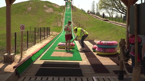 "AB park" attraction place in the region of Lielvarde, Latvia - May of 2019.  Young people with an inflatable camera sliding. The attraction with water slide rings. 