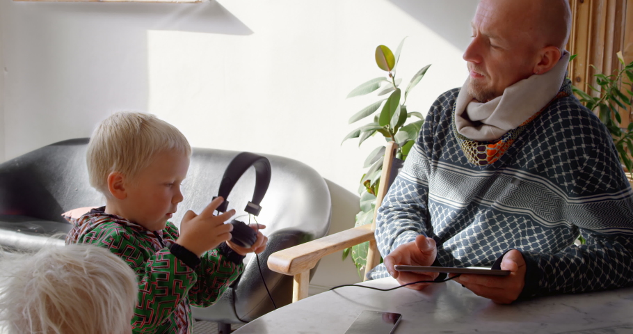 Front view close up of Caucasian father and children listening to music on digital tablet at home. Social distancing and self isolation in quarantine lockdown for Coronavirus Covid19