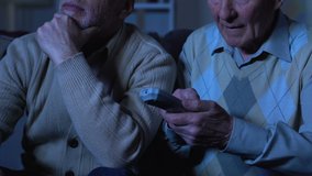 Two old men watching tv changing channels remote control, nursing home leisure