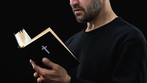 Bearded man reading holy bible, praying God against dark background, psalm