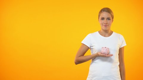 Positive female putting coin in piggybank, planning budget, financial savings