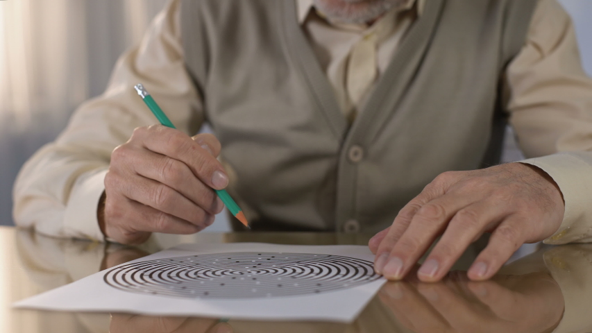 Concentrated retired man solving logic test at table, memory exercise, neurology Royalty-Free Stock Footage #1030541858