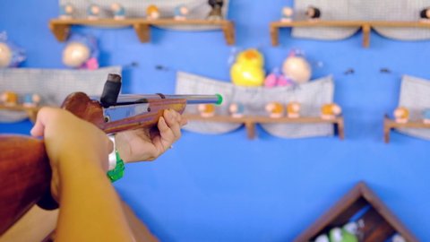 woman is playing a shooting game at festivals. and shooting a doll which is the target of this shooting game.