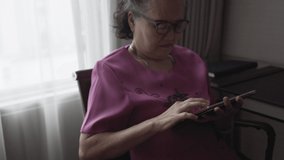 Asian senior woman using digital tablet in living room, learning and study concept
