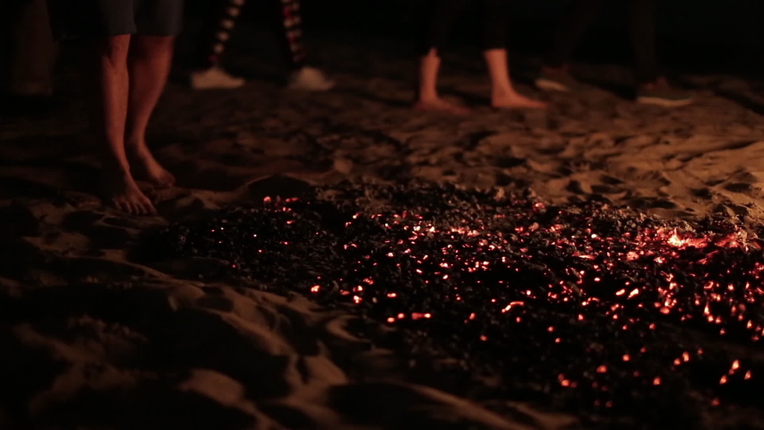 Man with bare feet resolutely walks over hot coals, many participants in ritual walk around. Sectarians perform rite of passage. Shaman teaches to walk on burning coals. Healer cleanses soul Royalty-Free Stock Footage #1030548098