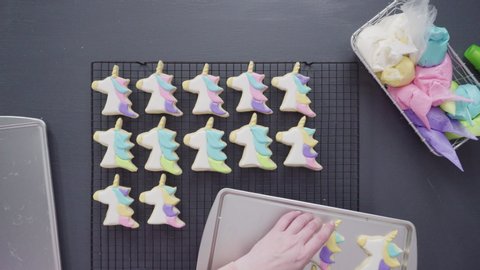 Step by step. Flat lay. Decorating unicorn sugar cookies with royal icing on baking sheet.