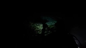 A silhouette of a scuba diver entering the water at night time using underwater torches