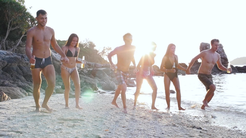 Group of friends spending time on the beach and making party. Having fun on a lonely tropical island
