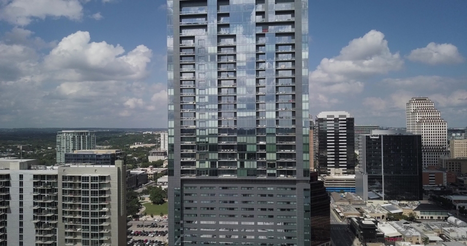Rising aerial shot of a reflective glass skyscraper on a sunny day in downtown Austin, Texas