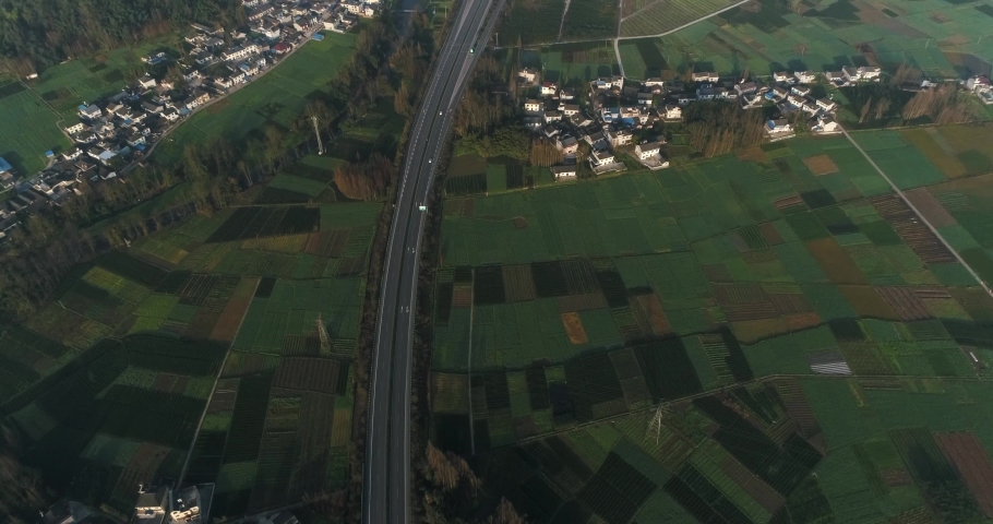 Aerial above view of countryside landscape of Sichuan China of village house crop field and cars driving on highway in sunny spring day