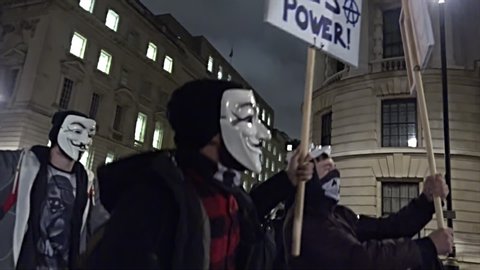 London, United Kingdom (UK) - 11 05 2015: Protestors wearing Guy Fawkes masks march at night carrying placards