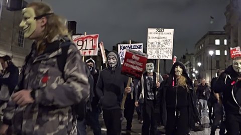 London, United Kingdom (UK) - 11 05 2015: Protestors wearing Guy Fawkes masks march at night carrying placards