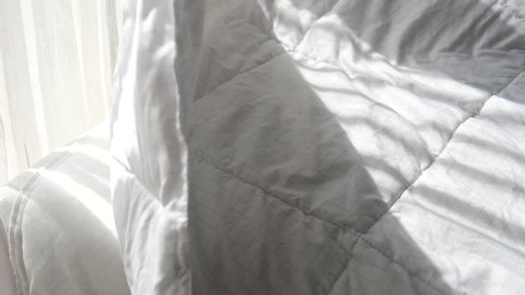 Opening white blanket from bed, slow motion.