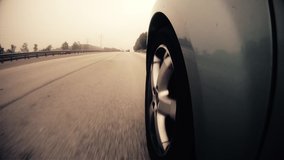 A highly stylized clip of a car speeding down the highway on the German autobahn. Highway wheel warm grade.