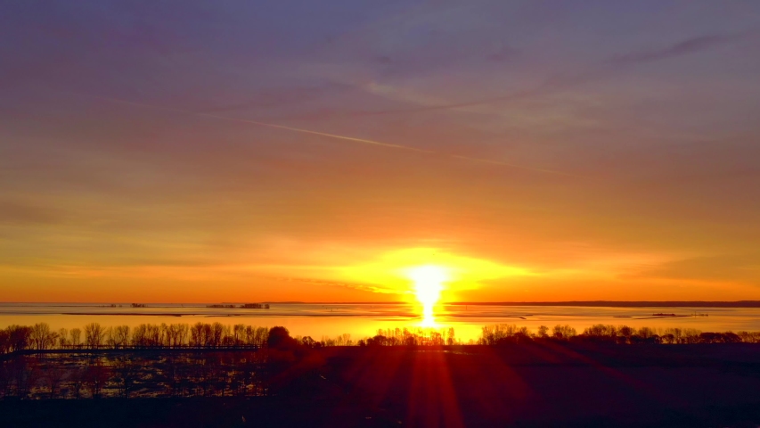 Colorful sunrise sky as seen through grid of power cables and poles, spectacular moving drone view.