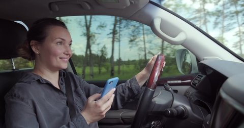 Woman gets into an accident on the car.  Dangerous situation on the road. Woman drives the car and typing text on the smartphone. Adult Woman in the car using mobile phone while driving. Real time. 