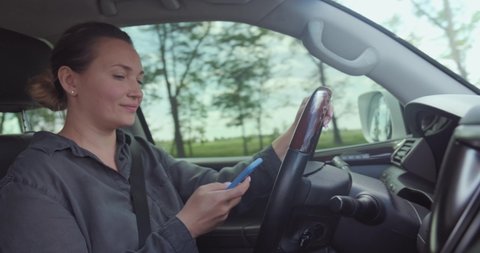 Woman gets into an accident on the car.  Dangerous situation on the road. Woman drives the car and typing text on the smartphone. Adult Woman in the car using mobile phone while driving. Real time. 