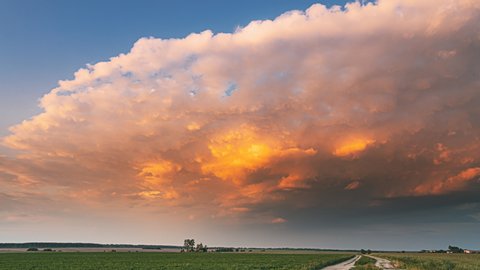 Стоковое видео: Dramatic Colorful Sunrise Sky Before Approaches Spring Storm Above Landscape With Rural Country Road Through Green Field And Meadow. Pathway, Way, Open Road In Agricultural Early Summer Season
